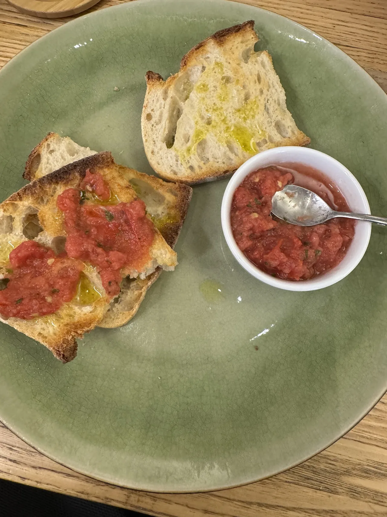 A plate of toast with tomato spread and a small bowl of sauce