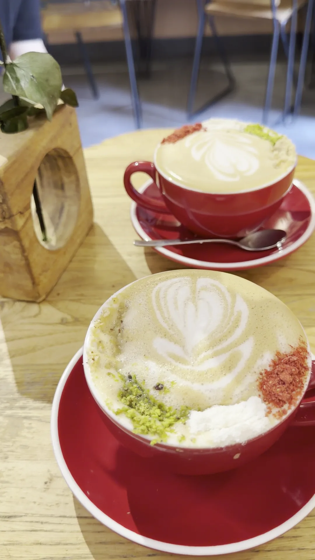 Two red cups of coffee with latte art stacked on saucers