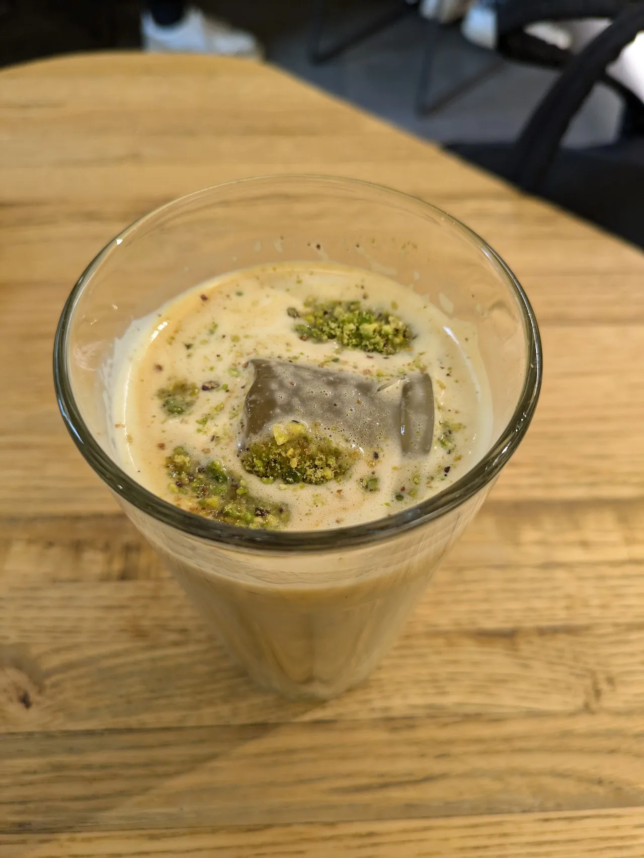 An iced coffee drink in a glass with a pistachio garnish