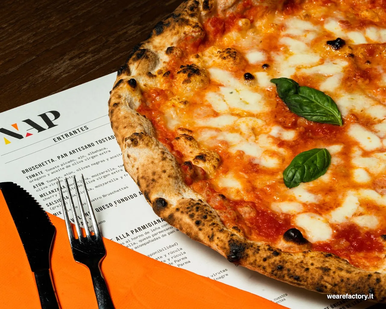 A margherita pizza with mozzarella and basil on an orange placemat