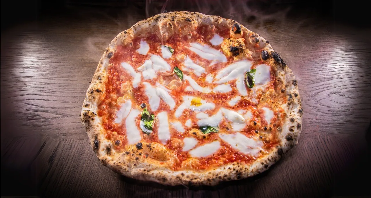 A whole pizza with tomato sauce and white mozzarella on a dark background