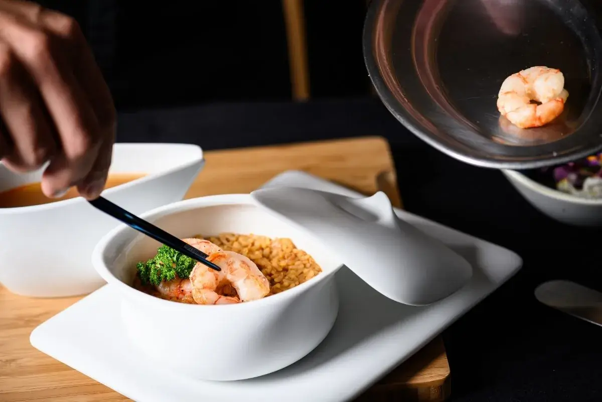 Shrimp and rice in a white lidded bowl, garnished with broccoli, at Negresco Princess Rooftop