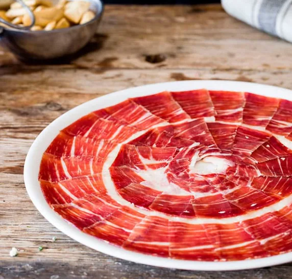 A plate of thinly sliced cured ham arranged in a spiral