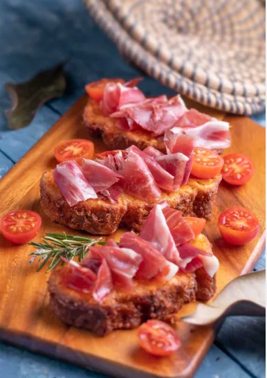 Toasted bread topped with prosciutto and cherry tomatoes