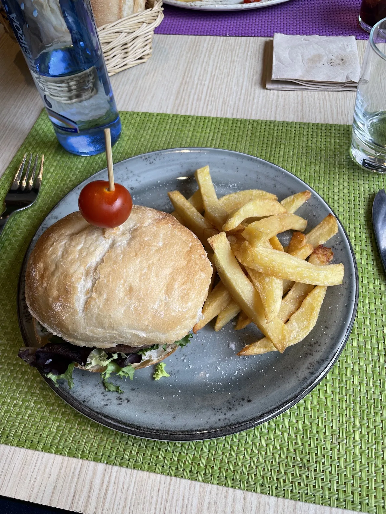 A burger on a plate with a side of french fries