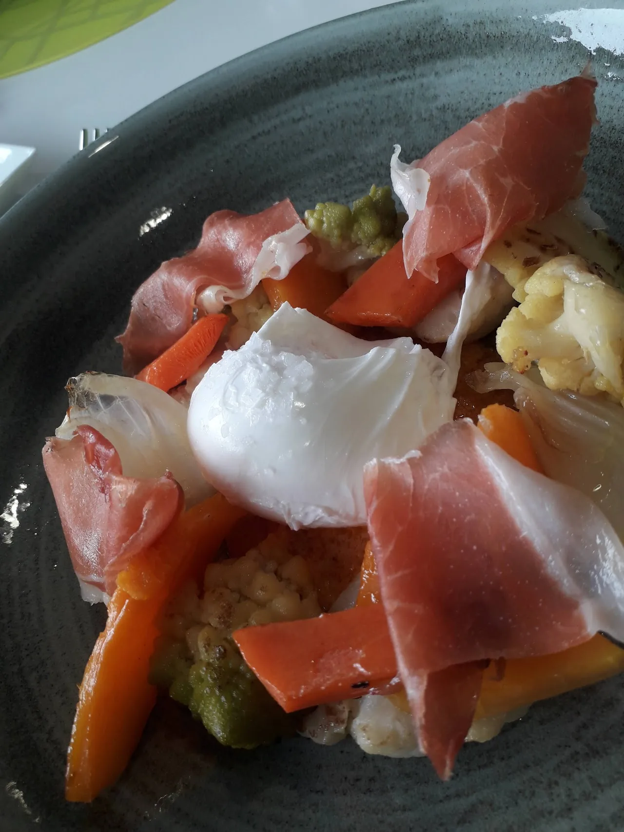 Poached egg with cured ham, roasted peppers and vegetables
