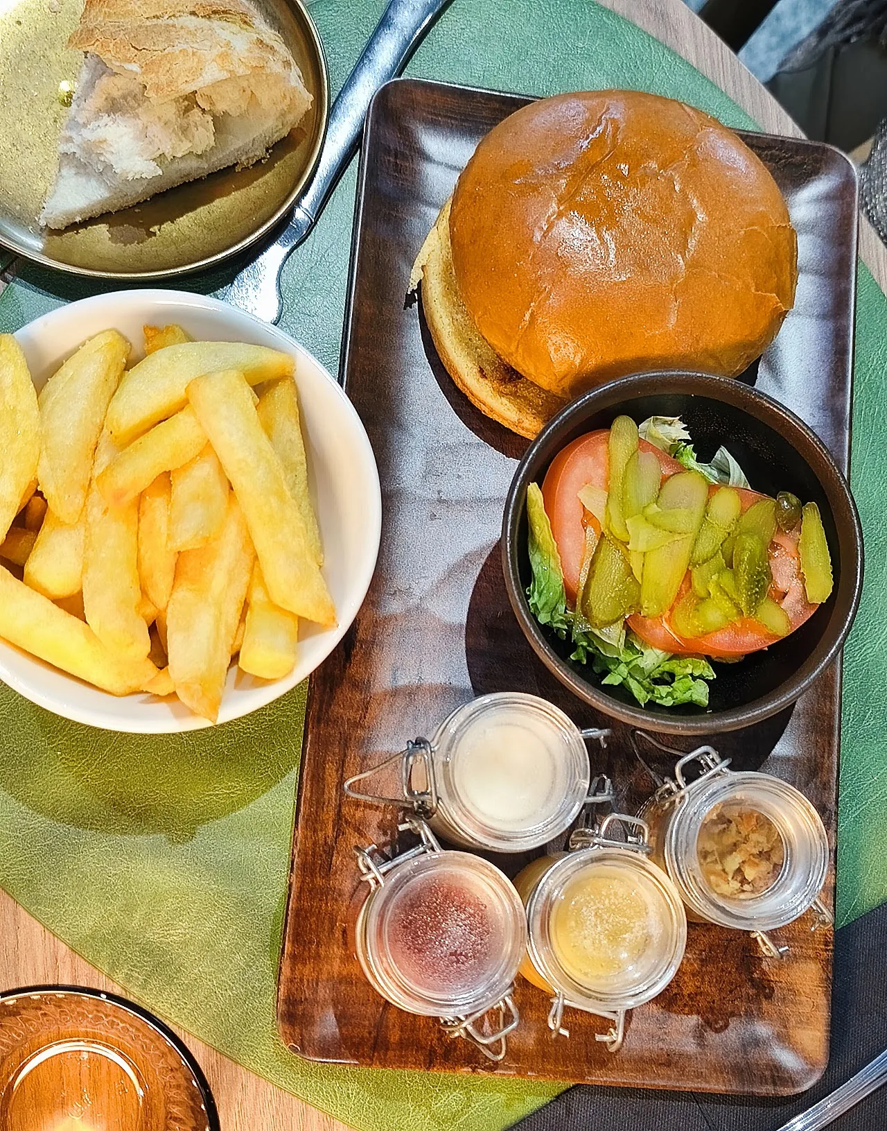 A burger with a side of fries and salad in wooden bowls