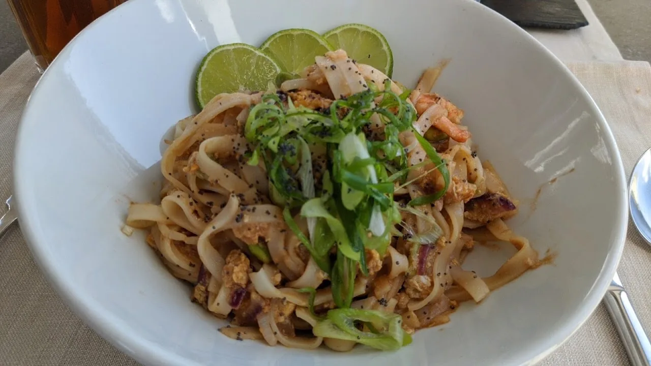 Stir-fried rice noodles with shrimp, scallion and lime wedges