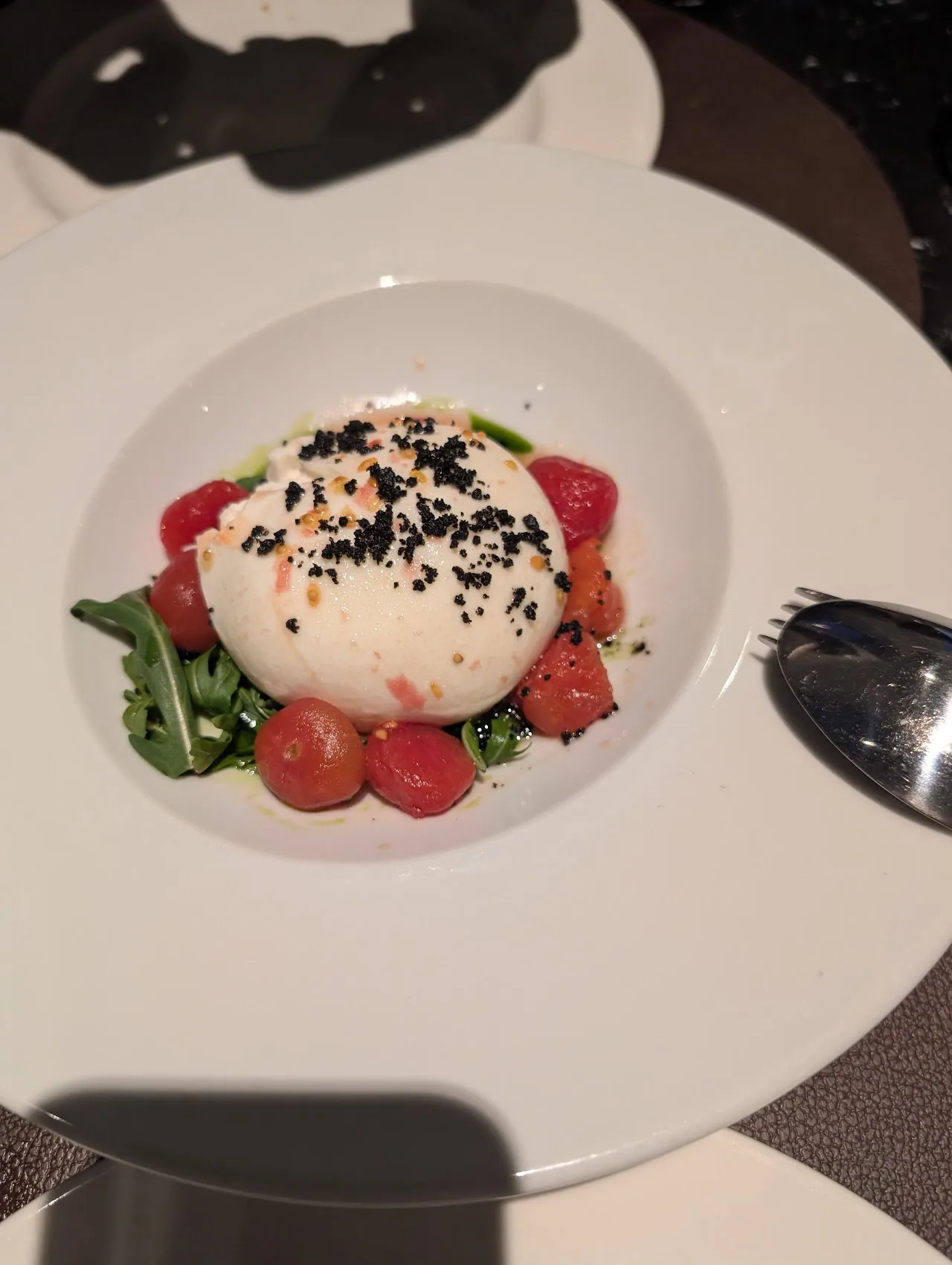 A ball of burrata with cherry tomatoes and greens