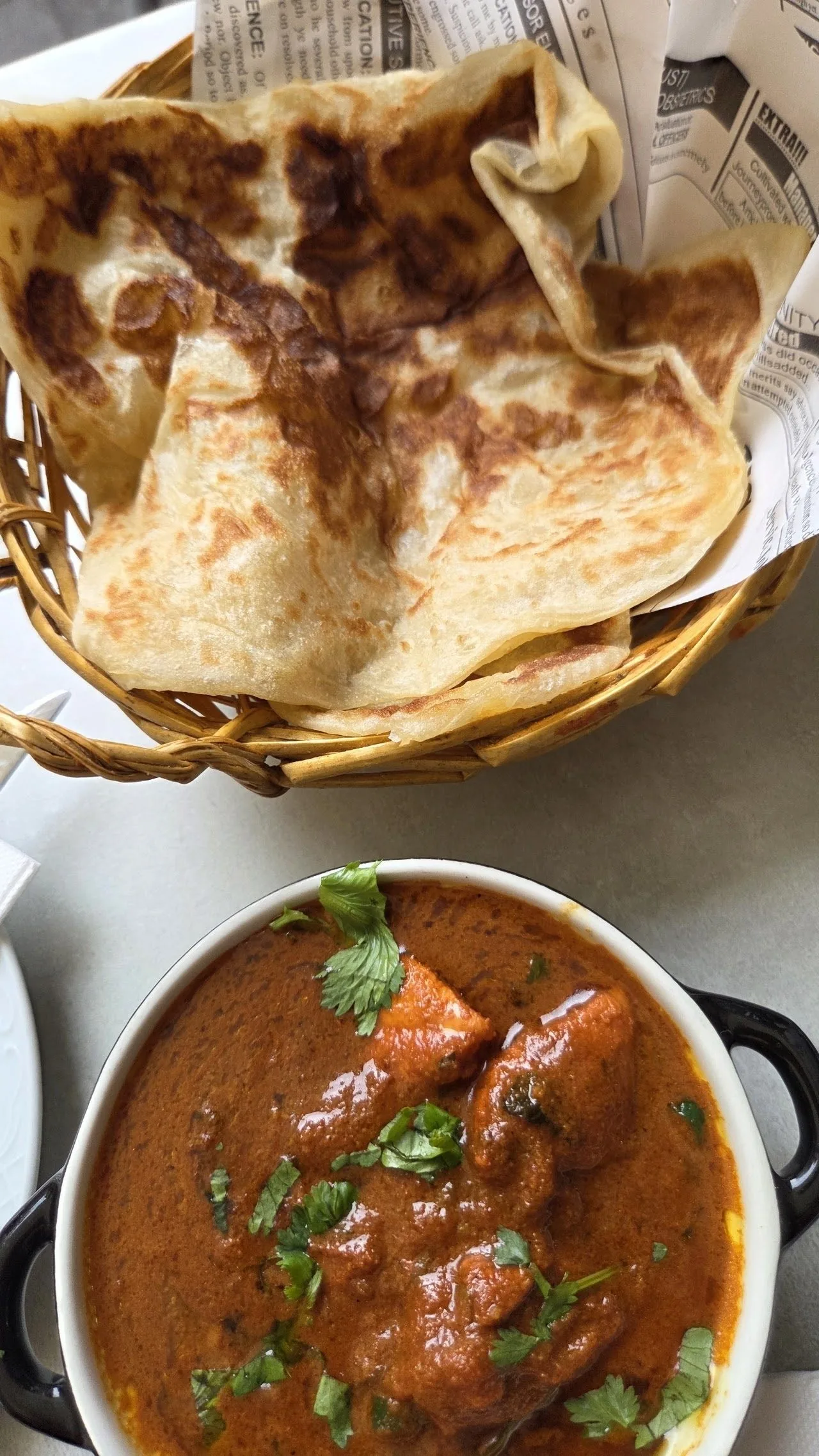 A basket of flatbread above a black pot of thick brown curry