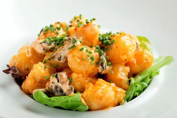 Crispy rock shrimp tempura tossed in a creamy spiced sauce and topped with chives, served on a bed of greens, at Nobu