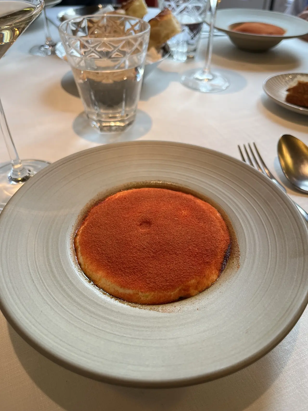 Round dish dusted with red spice powder on a plate, set on dining table
