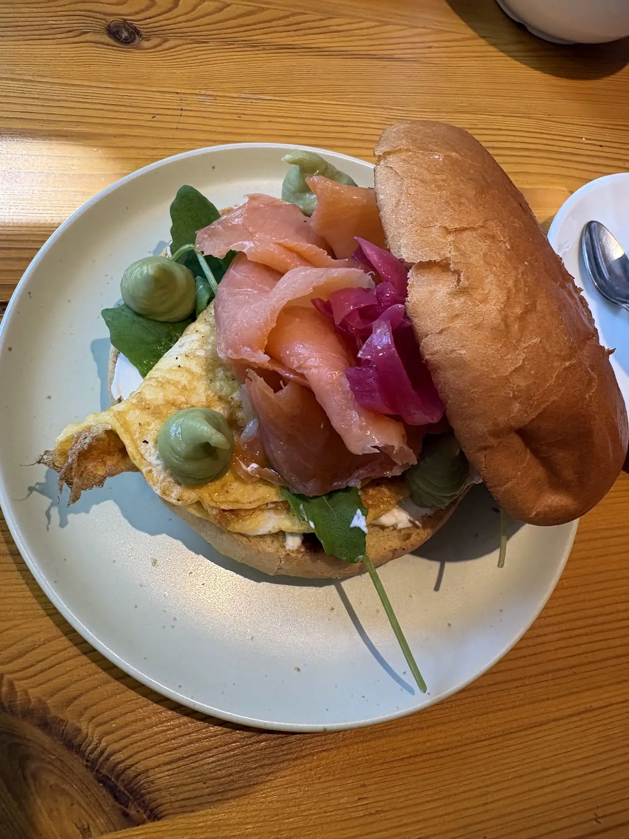 A bagel sandwich filled with smoked salmon and greens, served on a plate.