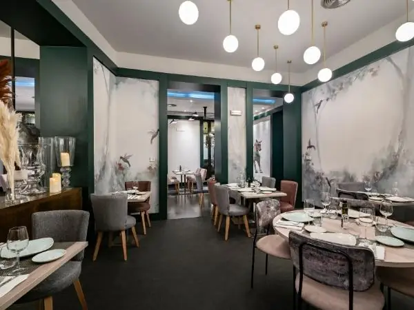 Green-walled dining room with painted botanical murals, globe pendant lights and set tables with grey velvet chairs