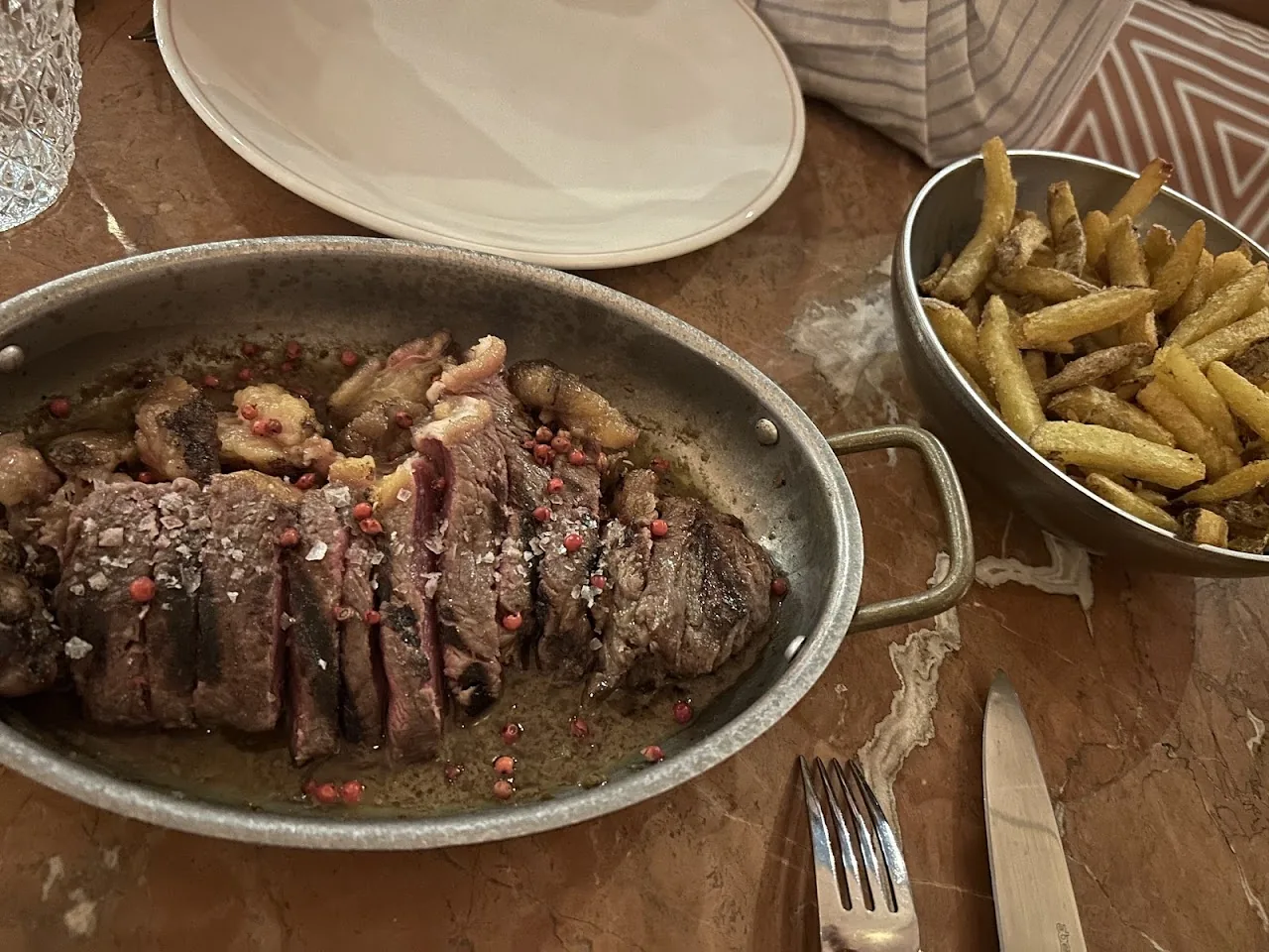 Sliced steak on a platter with a side of fries