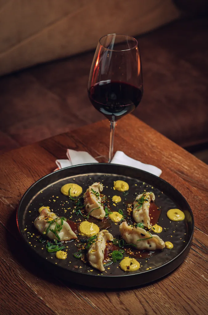 A plate of dumplings with a glass of red wine