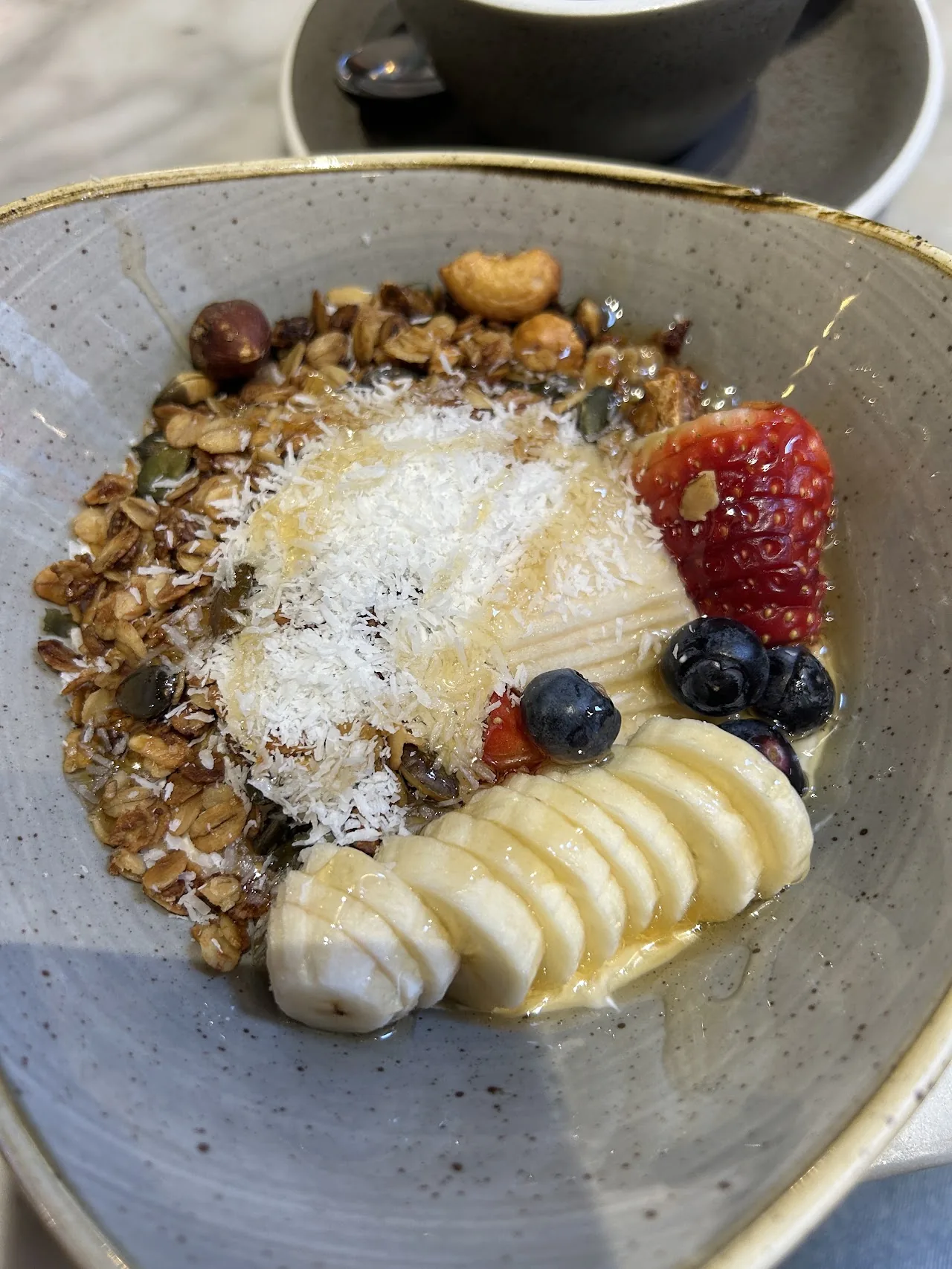 A bowl of granola with sliced banana, berries and shredded coconut