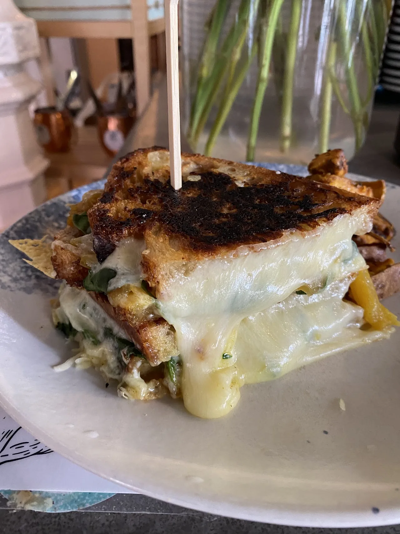 A toasted sandwich with melted cheese and a skewer, cut in half