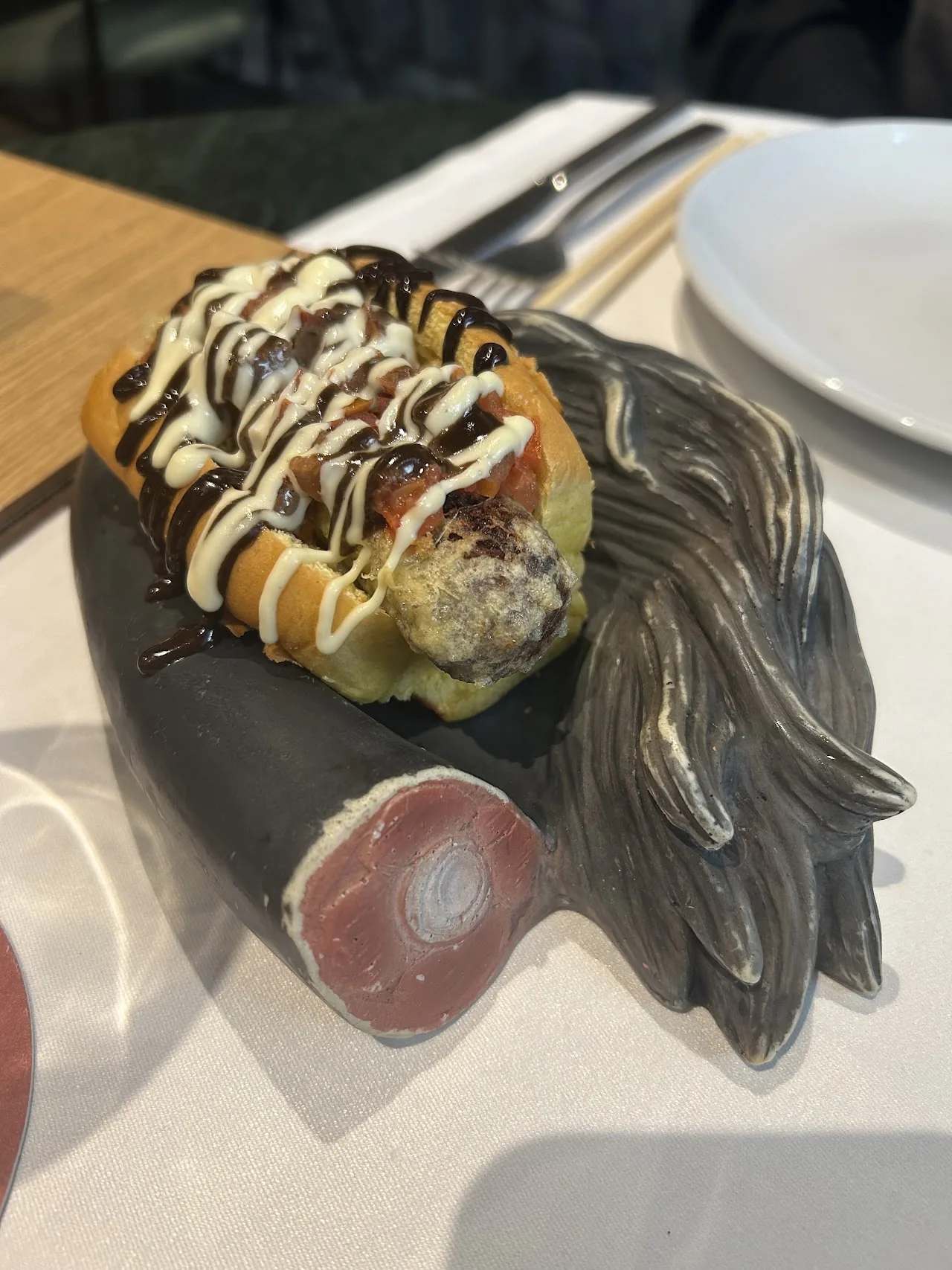 A dessert drizzled with chocolate sauce on a plate with a marshmallow garnish
