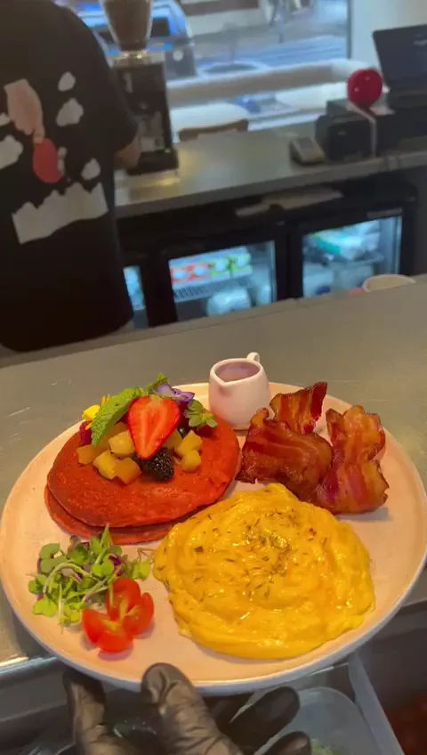 A breakfast plate with toast, bacon, a cheesy egg dish and berries
