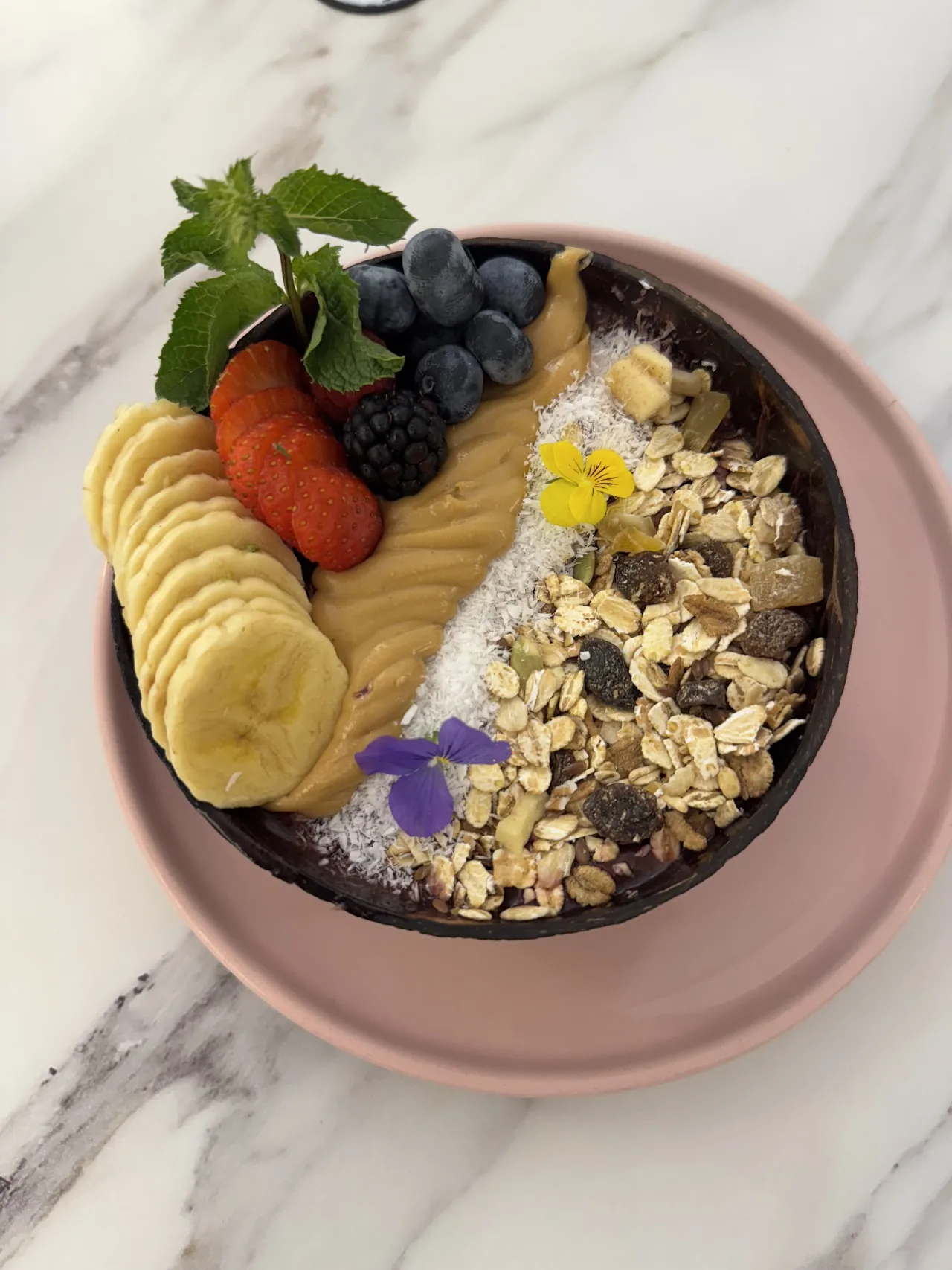A bowl of acai topped with banana, berries and granola