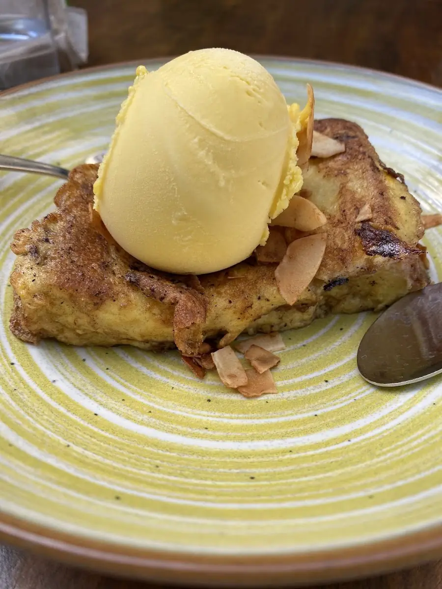 A NU dessert: a torrija topped with a scoop of ice cream on a green plate