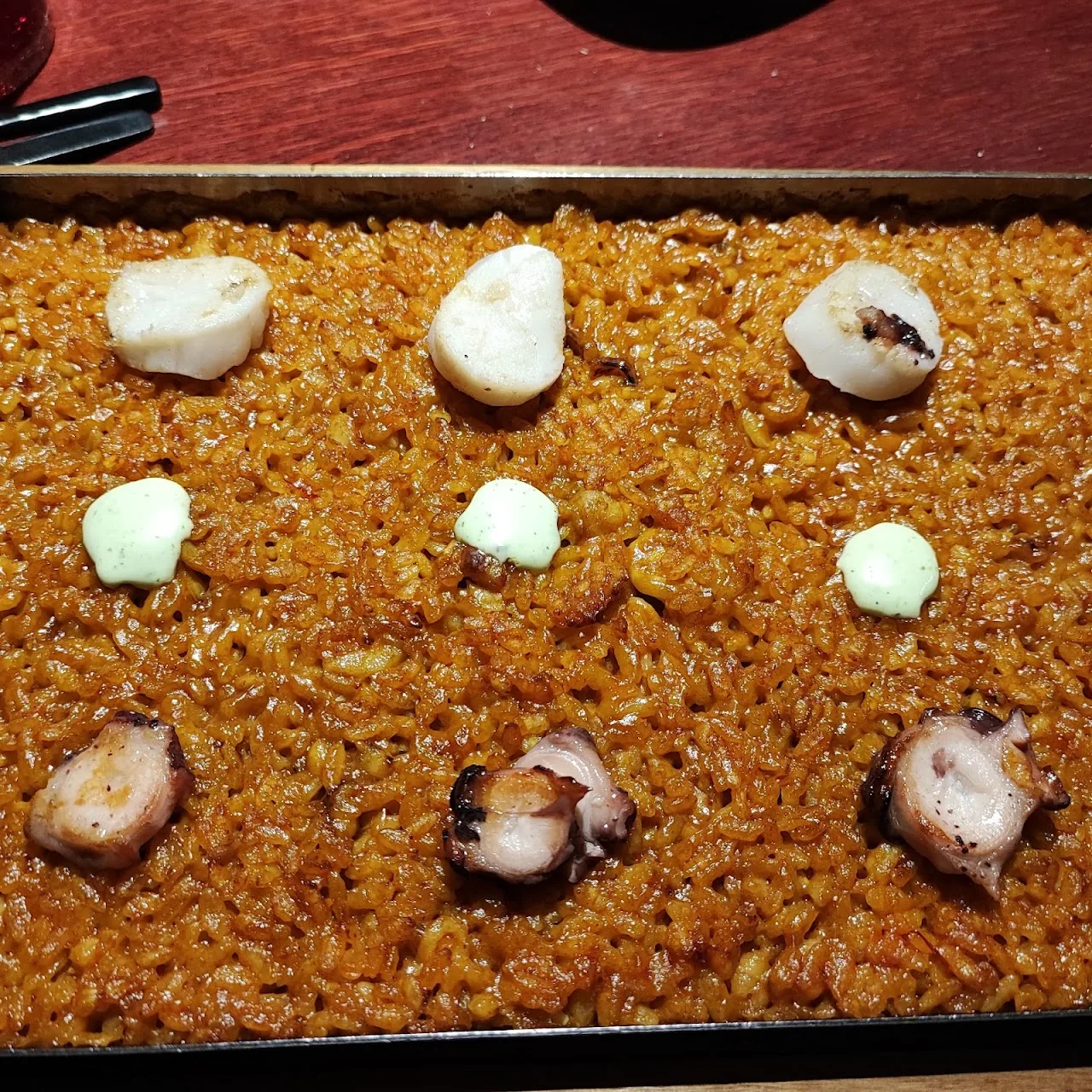 A rice dish with scallops in a paella pan