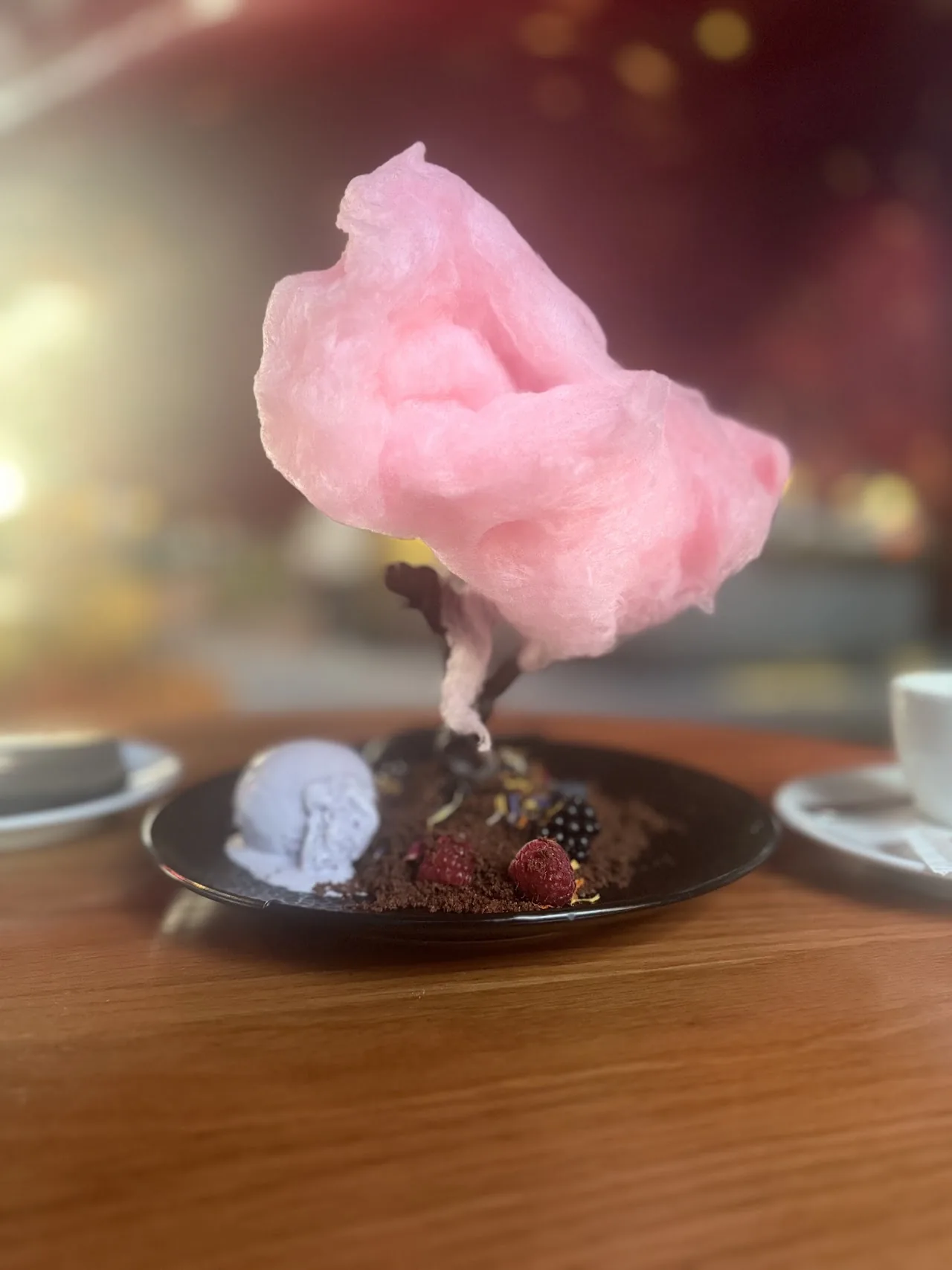 A dessert topped with pink cotton candy and berries
