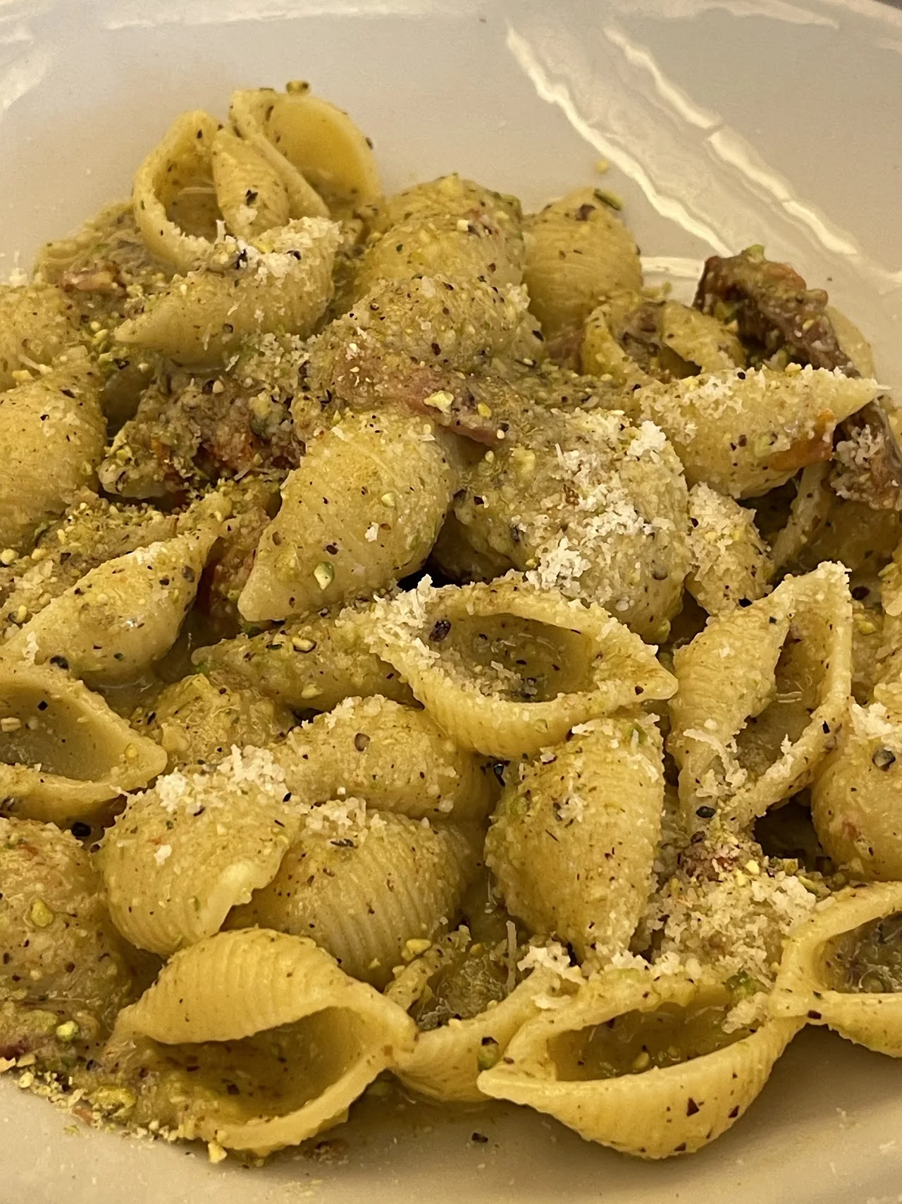 A bowl of shell pasta with pesto sauce and grated cheese