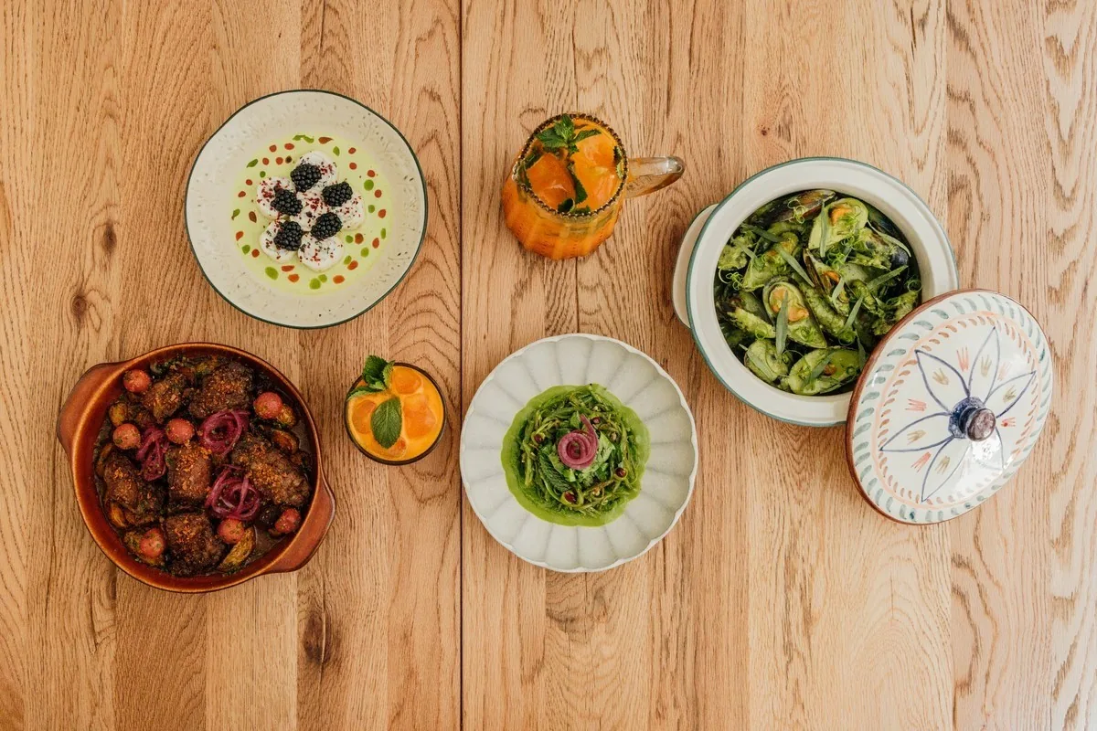 Several small dishes of colourful salads and dips on a wooden table