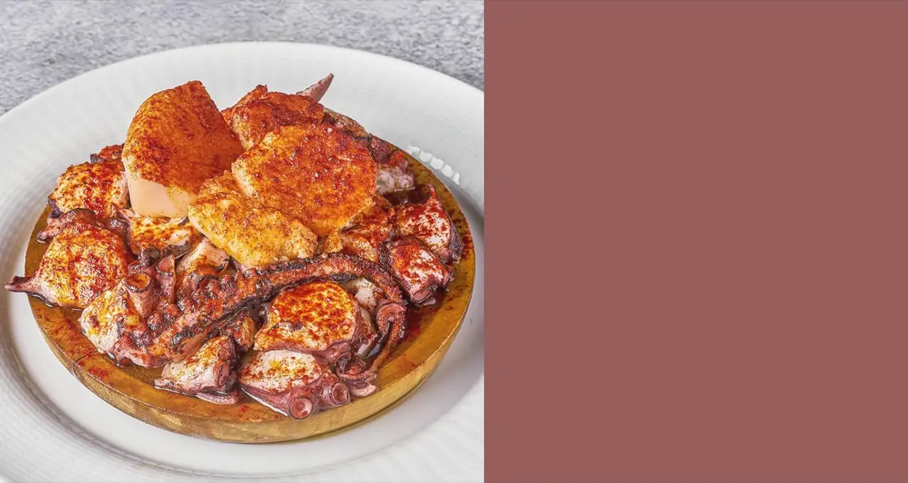 Pulpo a la gallega, sliced octopus and potato dusted with paprika and olive oil on a round wooden plate