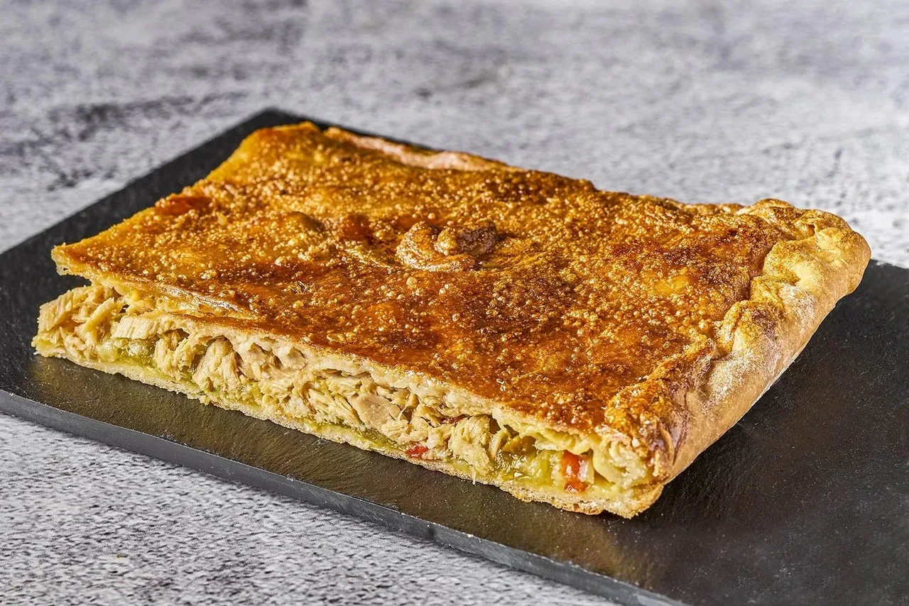 A rectangular golden baked pie on a dark slate board