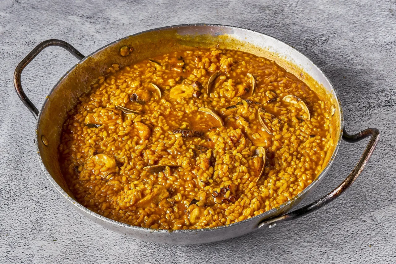 A round pan of orange rice seen from above on a grey surface