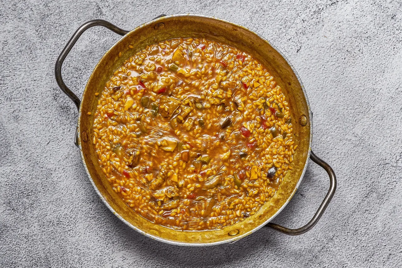 A round pan of dark brown rice seen from above on a grey surface