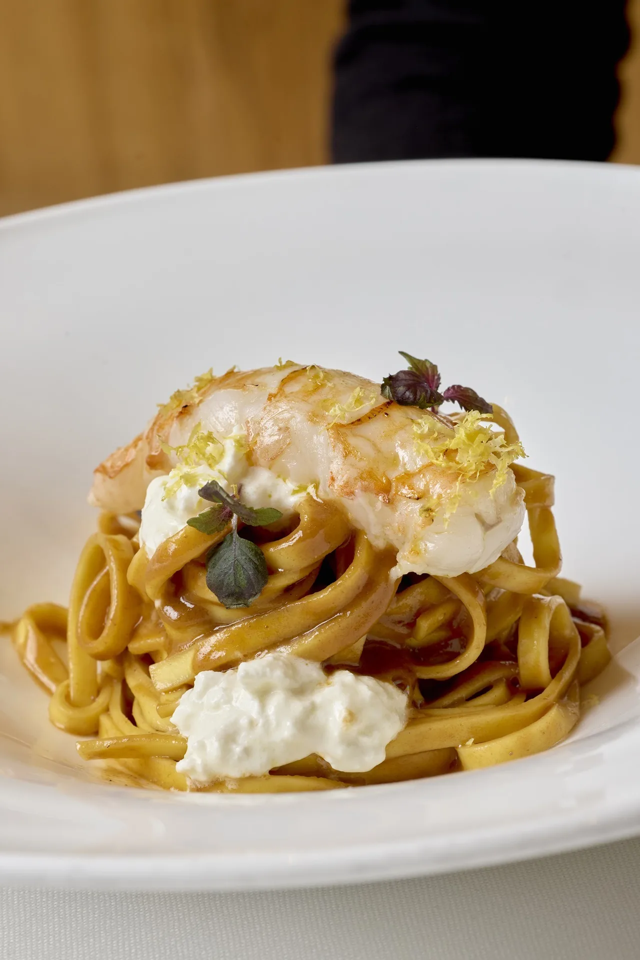 A plate of pasta topped with white cheese and seafood