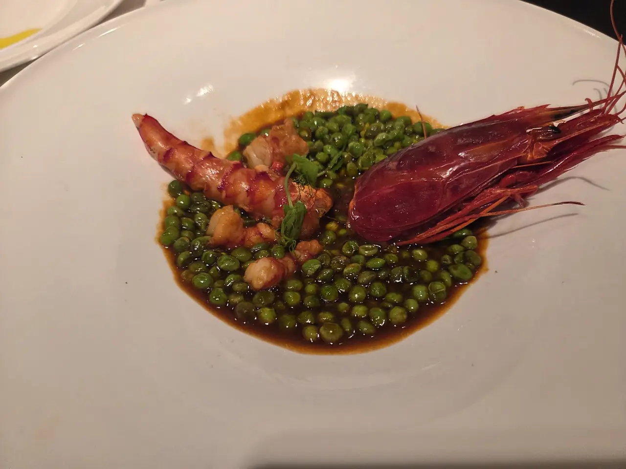 Plate of red prawn and peas in a dark sauce