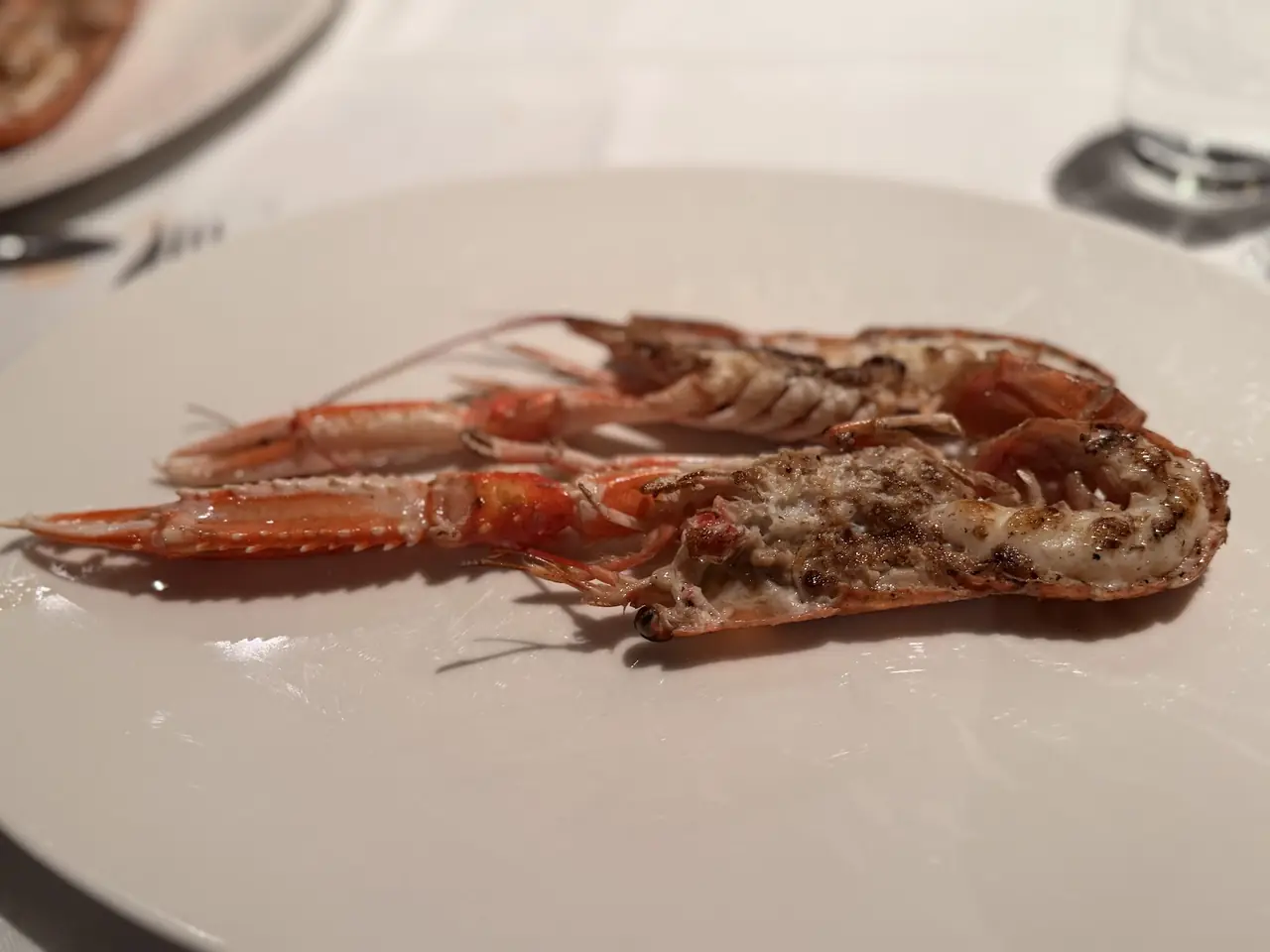 Two grilled langoustines split open on a plate