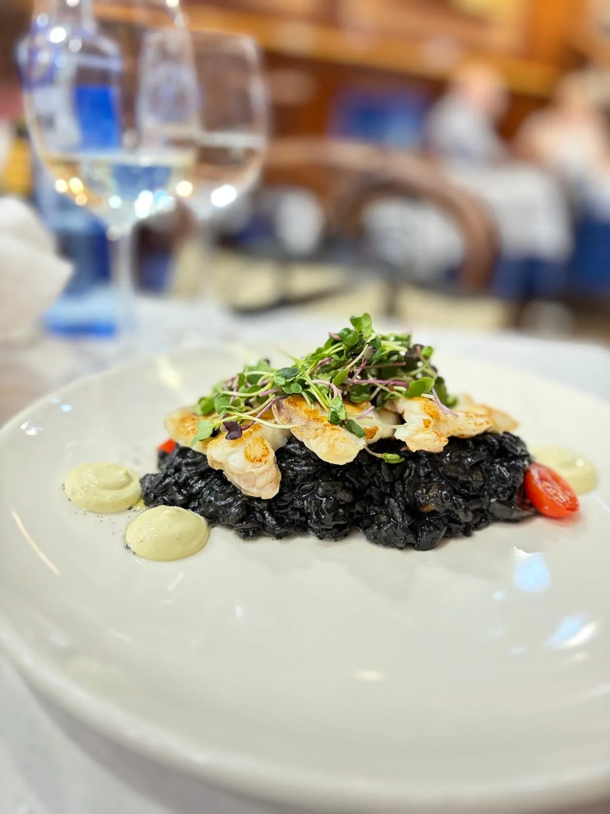 A plate of black squid ink rice garnished with fried onions
