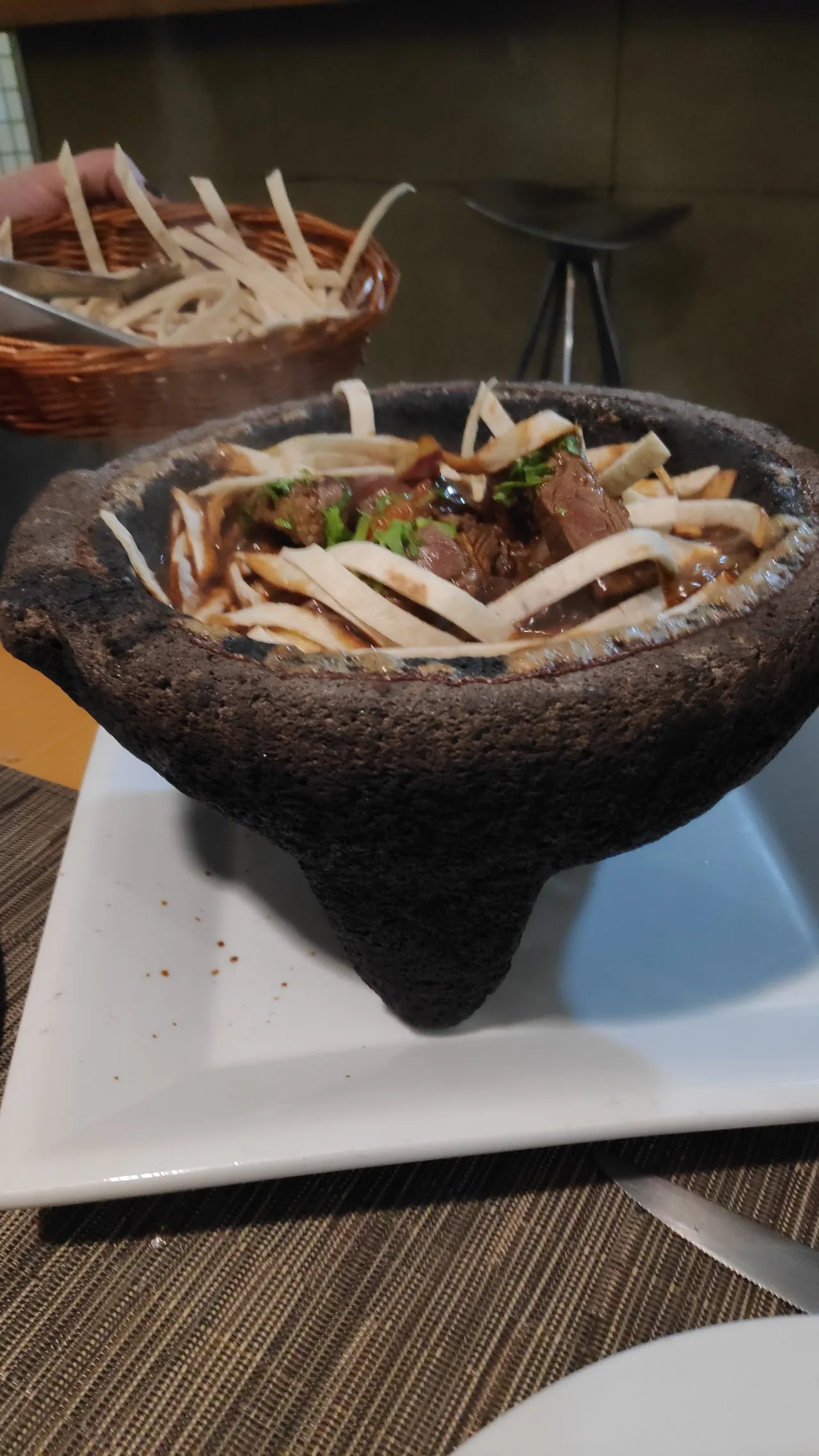 A ceviche served in a dark stone molcajete bowl garnished with strips of vegetables