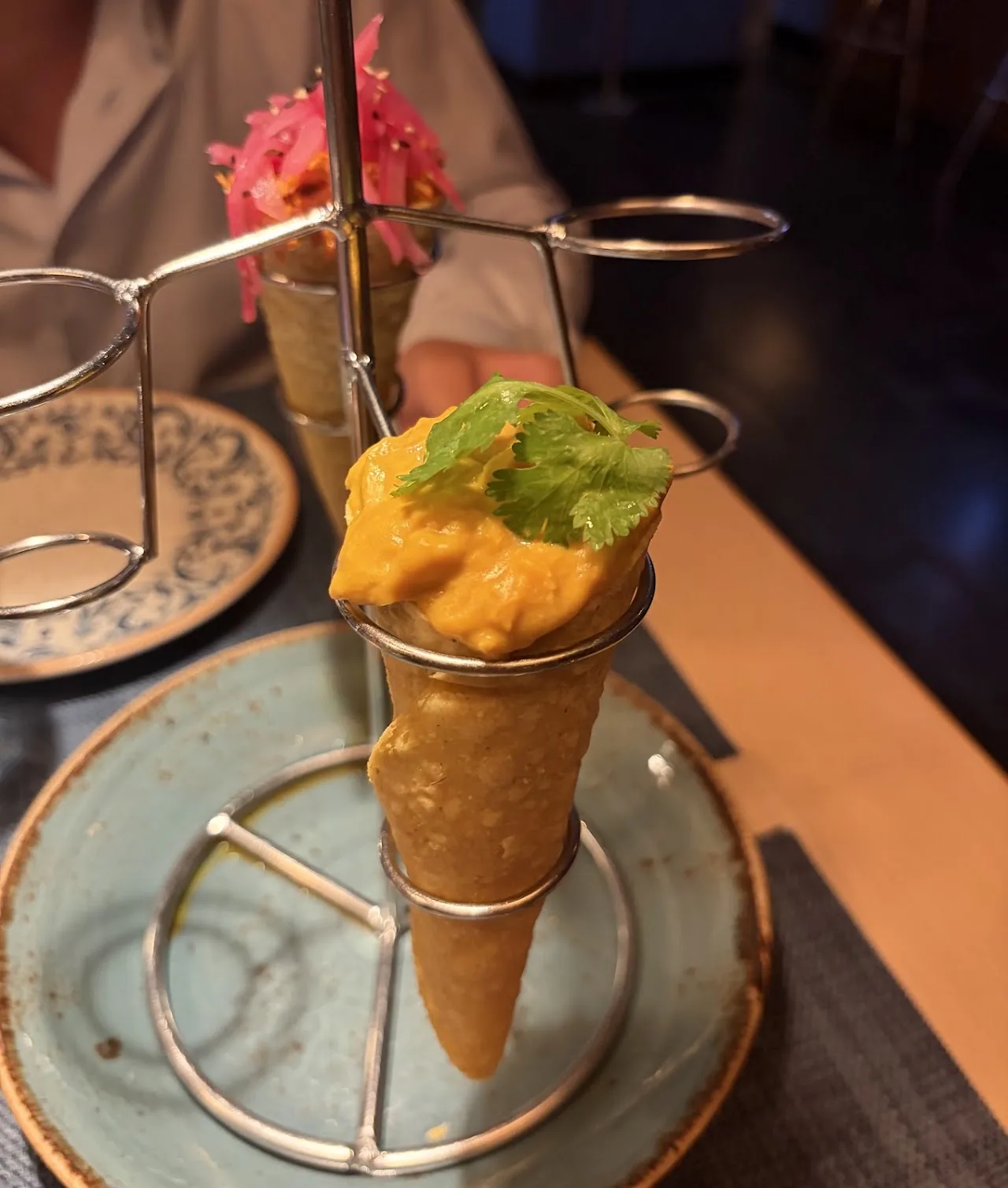 An ice cream scoop in a cone-shaped glass holder garnished with a small green leaf and pink flower