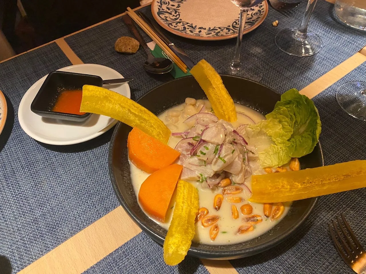 A bowl of ceviche with mango, avocado and plantain chips in a creamy sauce