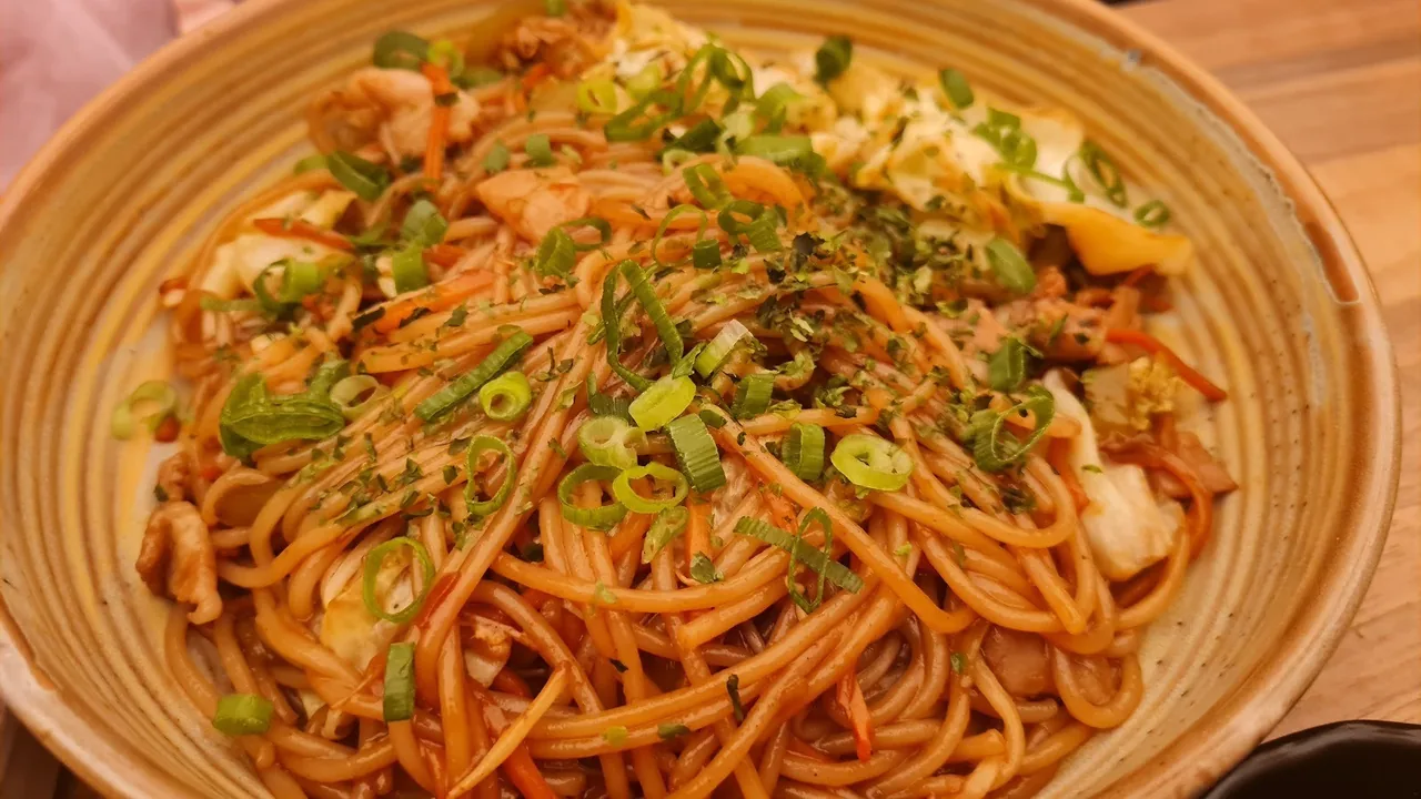 A bowl of noodles in a red sauce topped with spring onion