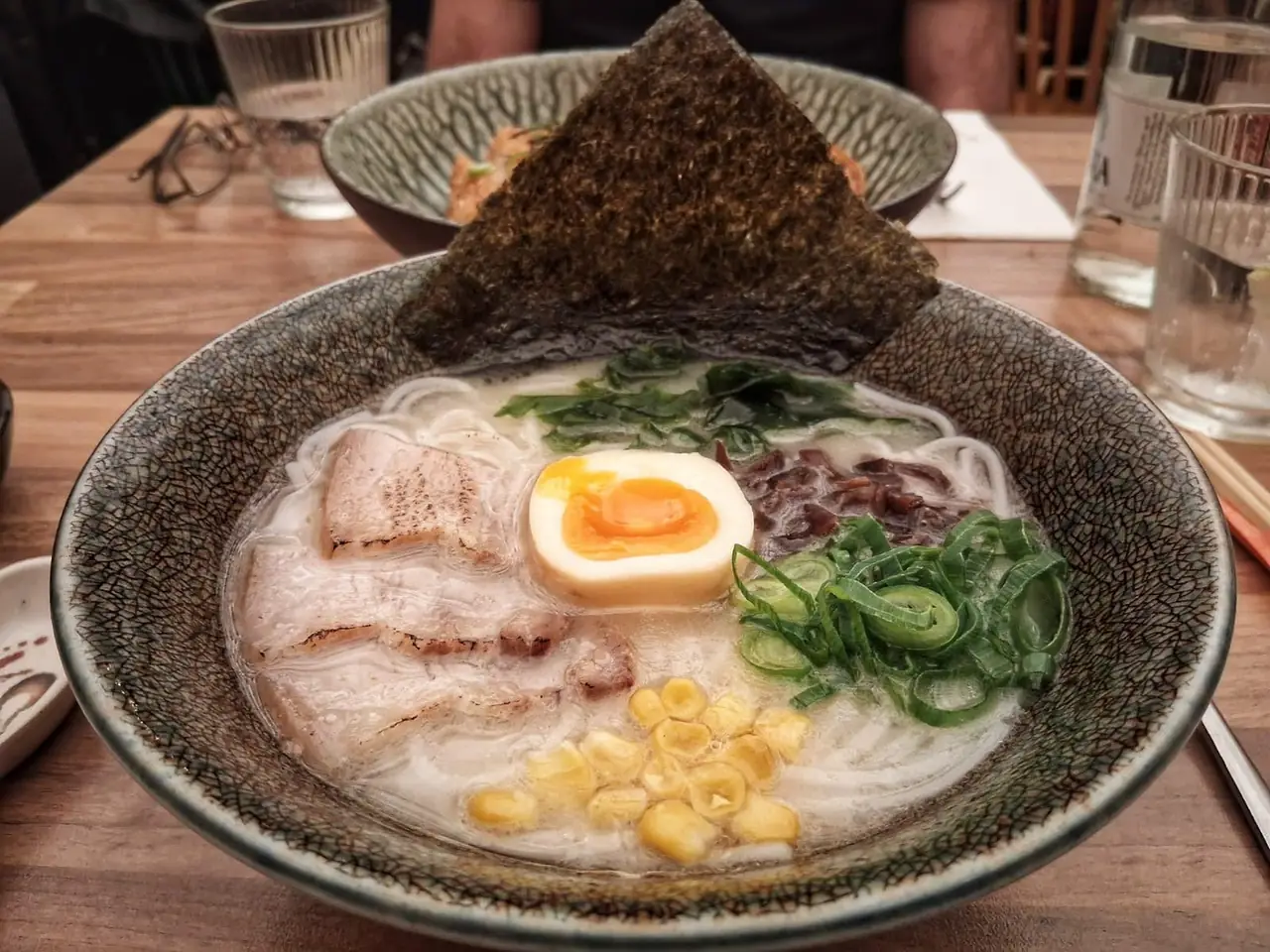 Tonkotsu ramen bowl with pork slices, egg, corn, scallion and a nori triangle