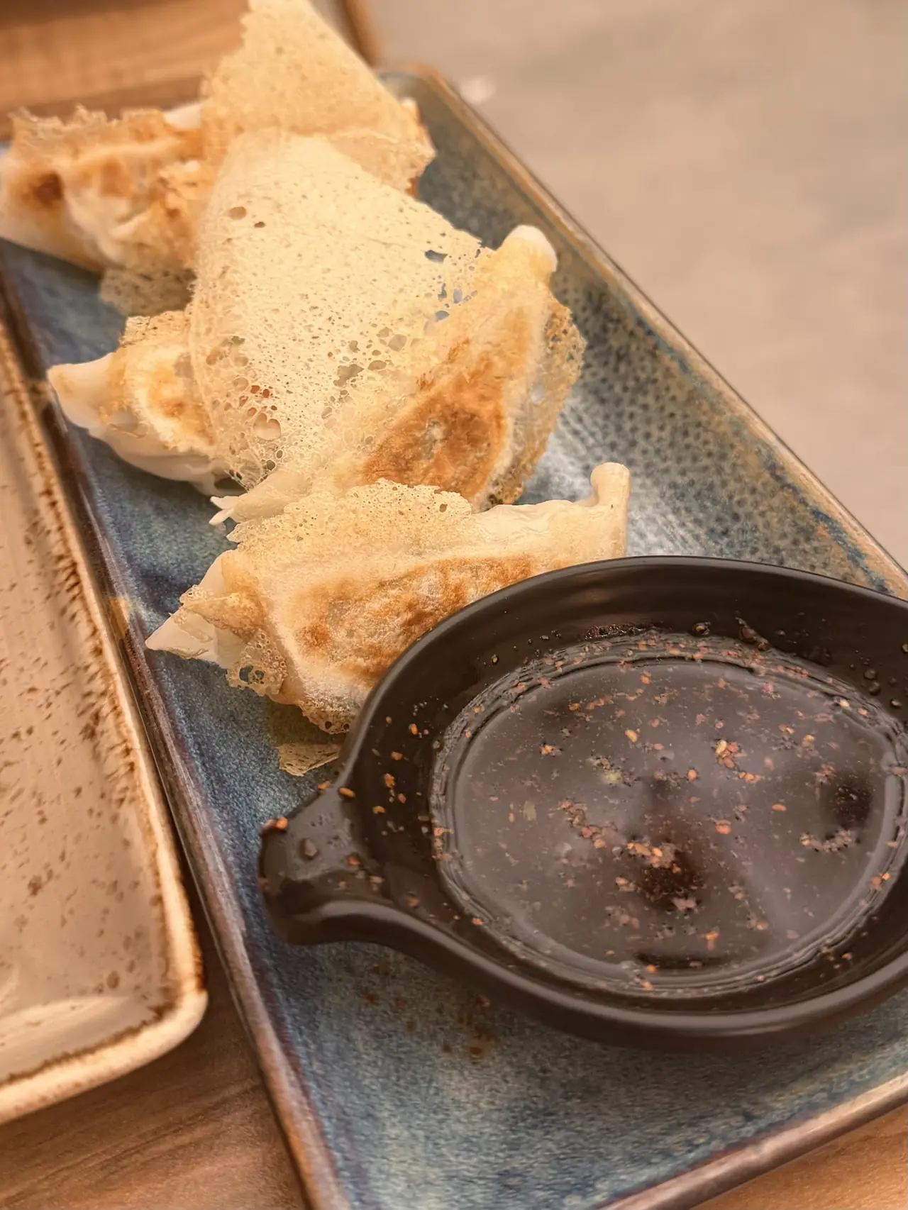 Crispy-skirted gyoza dumplings beside a dipping sauce