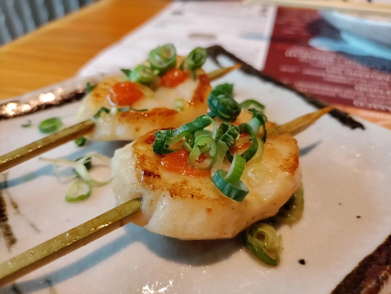 Two grilled scallop skewers with scallions and chili