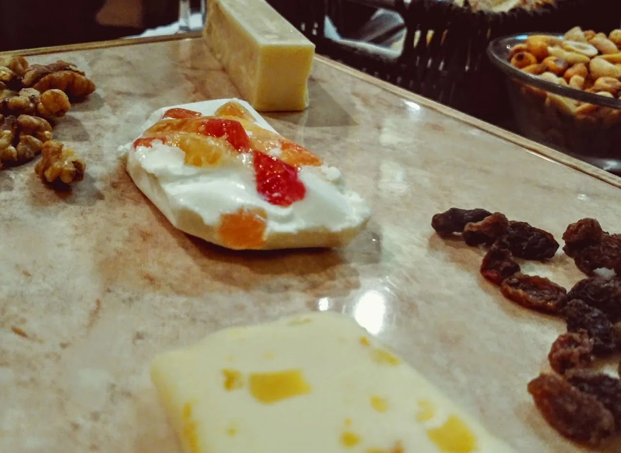 A small cheese board with a piece of cheese topped with fig jam and dried fruit