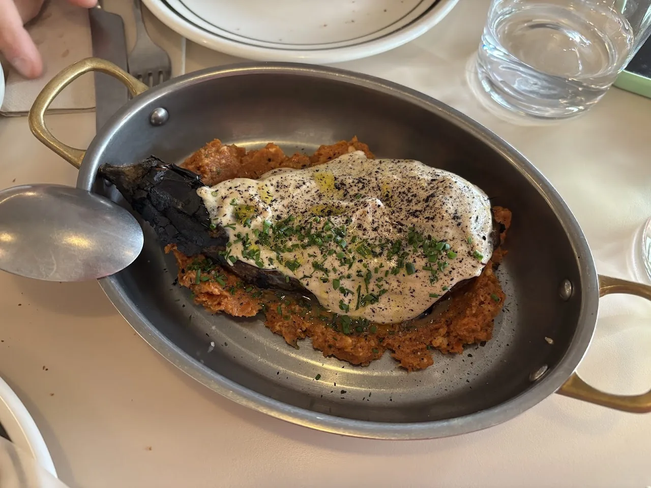 Whole roasted fish in a pan topped with sauce and herbs