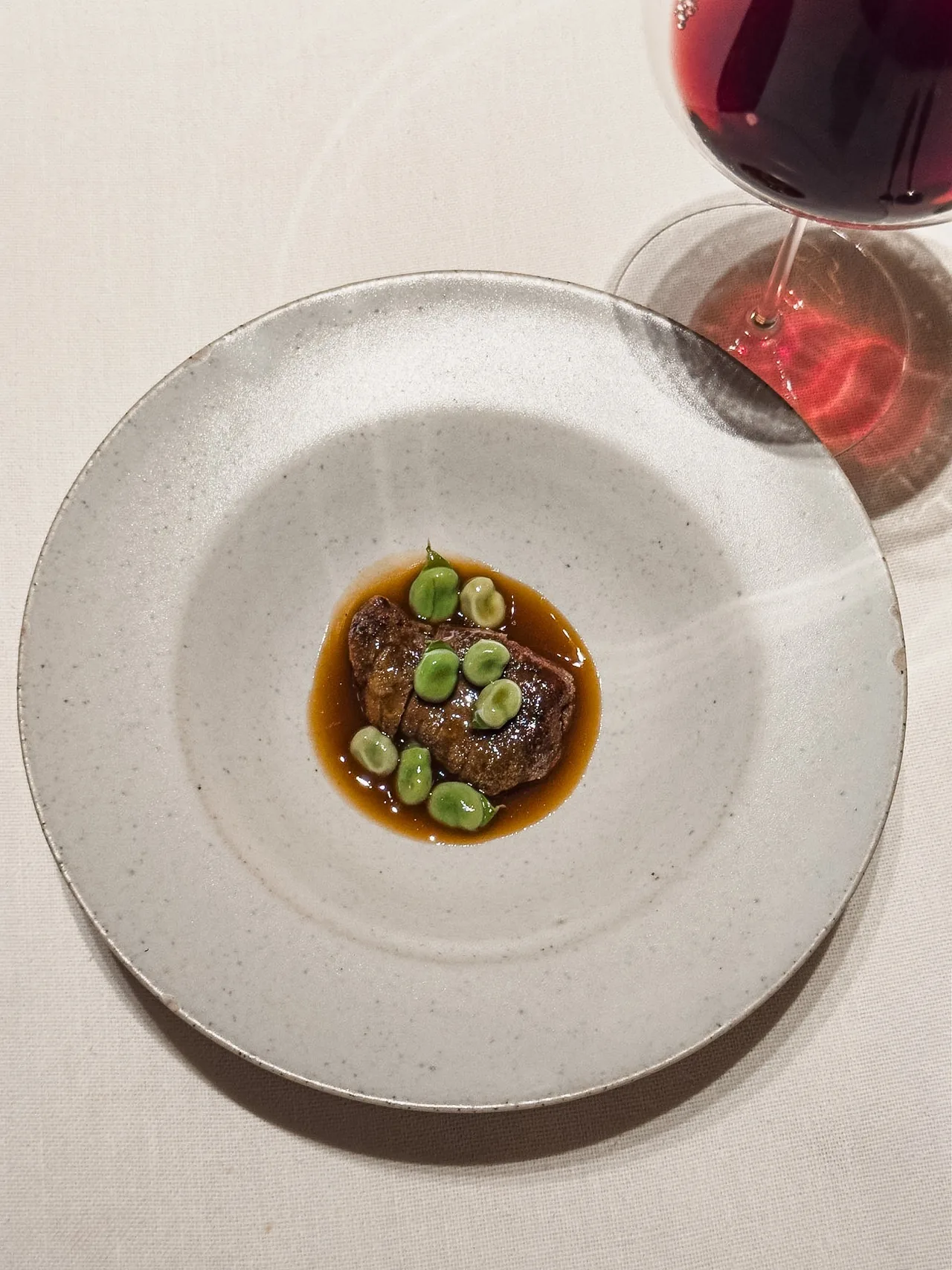 A round plate with a small portion of food with green beans in a brown sauce