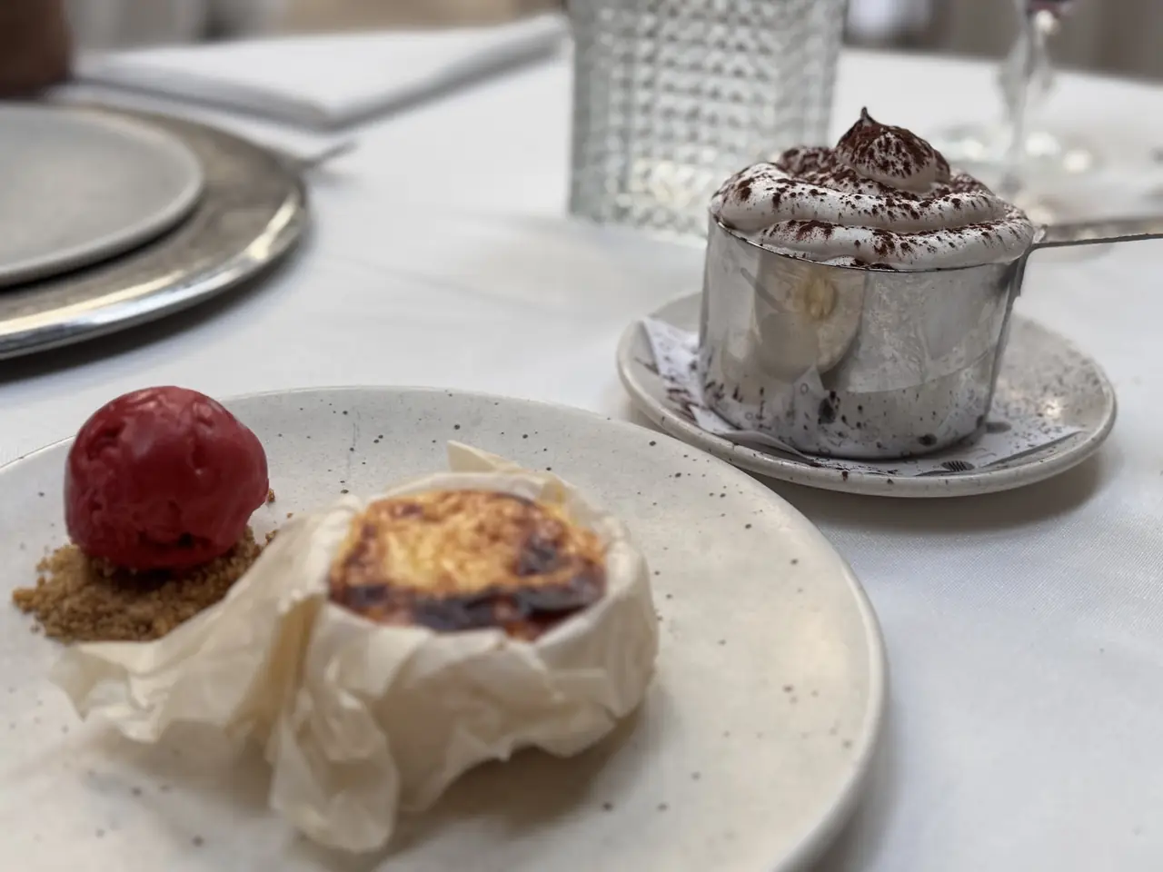 Baked cheese dessert with red sorbet and a whipped cream cup dusted with cocoa