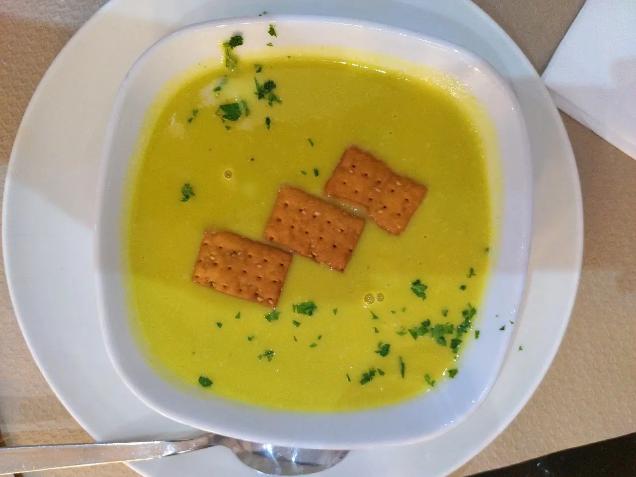 Bowl of creamy yellow leek-and-squash soup topped with crackers, at Ovo.